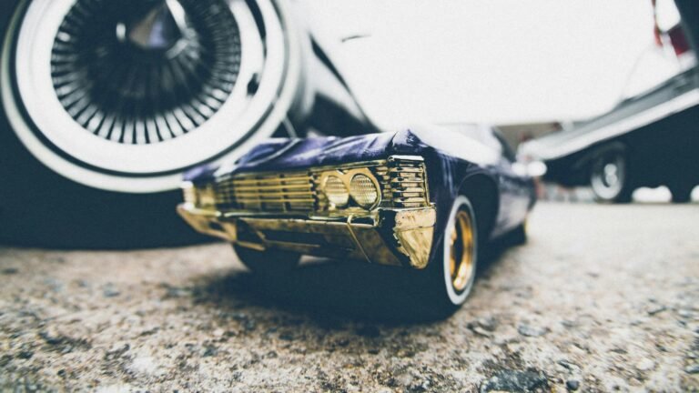 Low angle shot of a sleek vintage car model on a street with focus on the front grille and wheels.